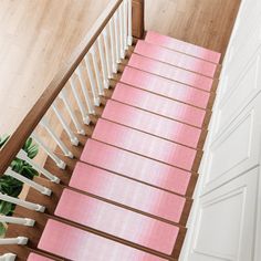 a stair case with pink carpet on the bottom and white railings, along with potted plants