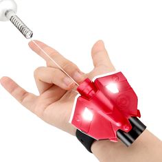 a hand holding a red toy with a light on it