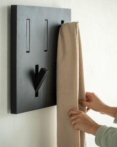 a woman is opening the curtain with her hand and pulling it up against the wall