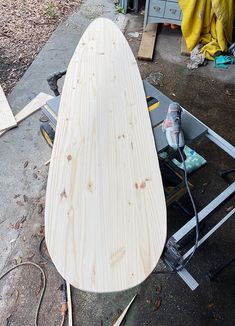 a wooden surfboard sitting on top of a table next to other woodworking tools