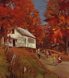 children running down a path in front of a white house surrounded by fall foliage and trees