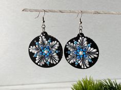 a pair of black and white earrings hanging from a wire next to a potted plant