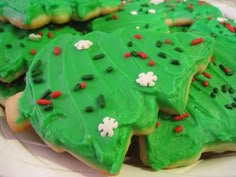 green decorated cookies on a plate with red and white sprinkles in the shape of trees