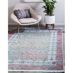 a living room area with a chair, rug and potted plant