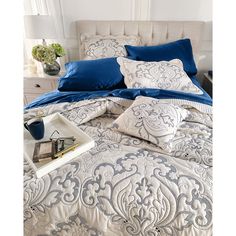 a bed with blue and white comforters in a bedroom next to a nightstand table