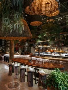 the interior of a restaurant with wooden tables and plants hanging from the ceiling above it