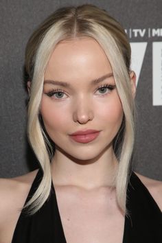 a woman with blonde hair and blue eyes wearing a black halter top is looking at the camera