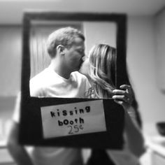 a man and woman kissing in front of a mirror with the words kissing booth on it