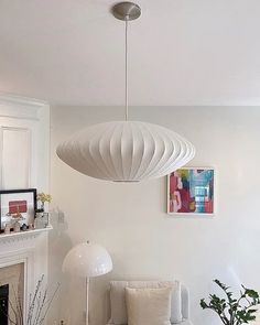 a living room filled with furniture and a white lamp hanging from the ceiling over a fire place