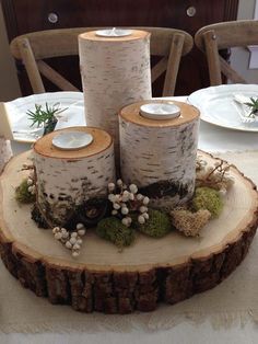 the table is set with white plates and candles on wood slices that have been cut in half