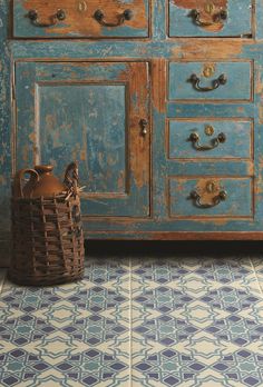 an old blue dresser with two baskets on it and a basket in front of it