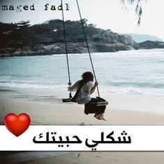 a woman sitting on a swing in front of the ocean with an i love you message