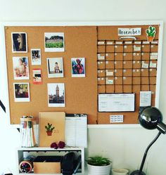 an office desk with a cork board on the wall and various pictures hanging on it