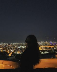 a woman standing in front of a city at night