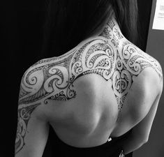 the back of a woman's shoulder with intricate tattoos on her upper and lower arm