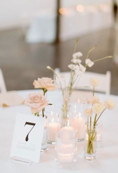 the table is set with candles and flowers in glass vases, which are labeled seven