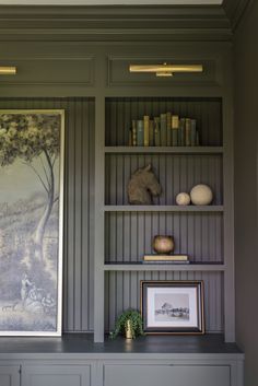 the bookshelves in this room are painted gray and have pictures on them as well