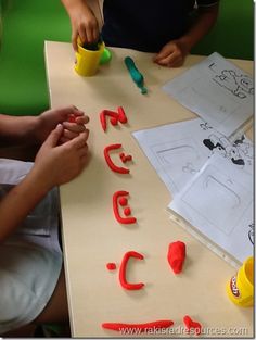 two children are sitting at a table making letters