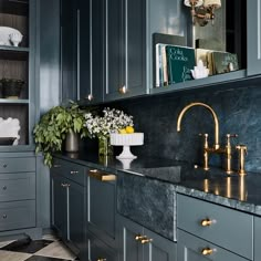 a kitchen with marble counter tops and gold faucets on the sink, surrounded by blue cabinets