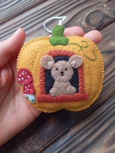 a hand holding a small felt ornament with a bear on it's face