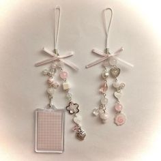 two tags with charms attached to them on a white surface