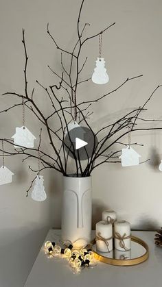 a white vase filled with lots of branches next to candles and christmas decorations on top of a table