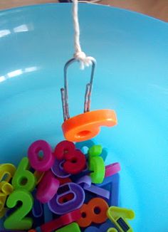 a bunch of magnets sitting on top of a blue bowl filled with letters and numbers