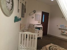 a baby's room with a crib and clock on the wall