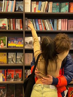 two people standing in front of a bookshelf with their arms around each other