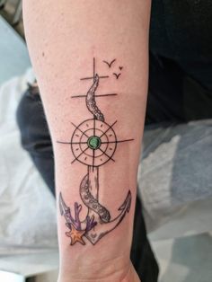 a woman's arm with an anchor, compass and seagull tattoo on it