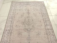 an antique rug is on the floor in a room with marble floors and white walls