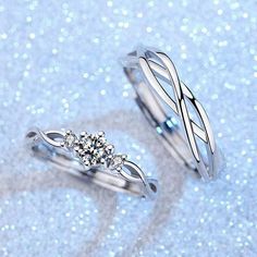 two silver rings with diamonds on them sitting on glittery blue surface in front of the camera