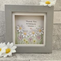 a white and yellow flower sitting next to a gray frame with the words thank you for helping me bloom