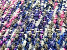 a close up view of a multicolored knitted rug with yarn spools