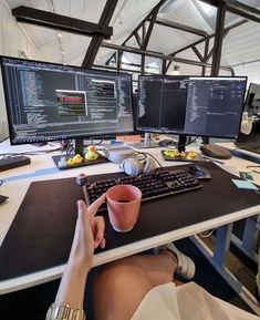 a person sitting at a desk with two computer monitors and a keyboard in front of them