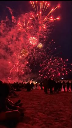 people are sitting on the beach watching fireworks