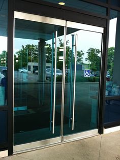 an empty parking lot with glass doors on both sides and cars parked in the background