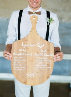 a man holding up a wooden paddle with writing on it and a bow tie around his neck