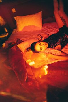 a woman laying on top of a bed next to candles