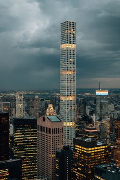 an aerial view of the city at night with skyscrapers lit up and dark clouds in the background