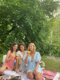 three women sitting on a blanket at a picnic