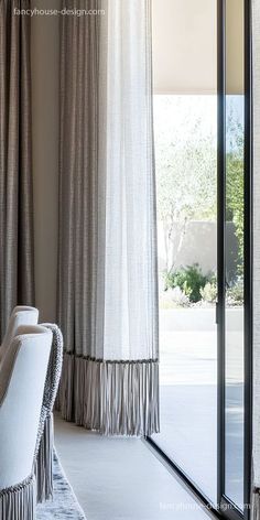 a living room filled with furniture next to a window covered in white drapes and curtains