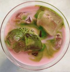 a glass filled with soup and vegetables on top of a table