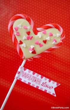 a heart shaped lollipop on a stick with a sign that says with love