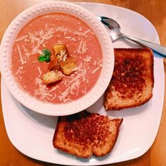 there is a bowl of soup and two pieces of bread on the plate