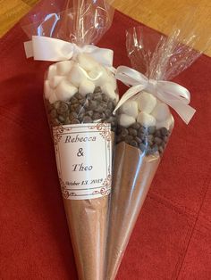 two cones filled with chocolate and marshmallows on top of a red table