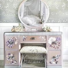 a vanity with flowers painted on the side and a mirror above it, in front of a wallpapered background