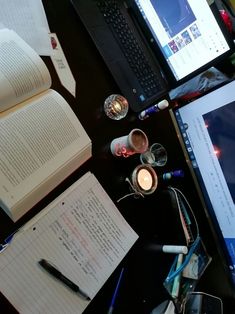 an open laptop computer sitting on top of a desk next to a notebook and pen