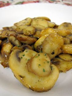 a white plate topped with sliced bananas covered in gravy on top of a floral table cloth