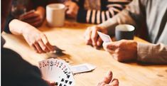 three people sitting at a table playing cards